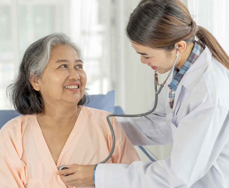 A doctor listens to an elderly woman's heartbeat with a stethoscope.