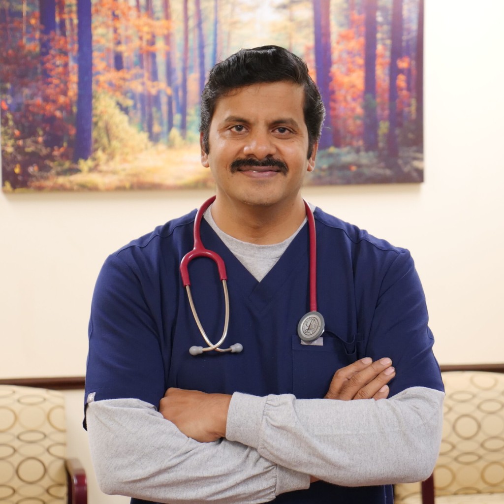 Smiling male doctor with stethoscope in clinical setting.